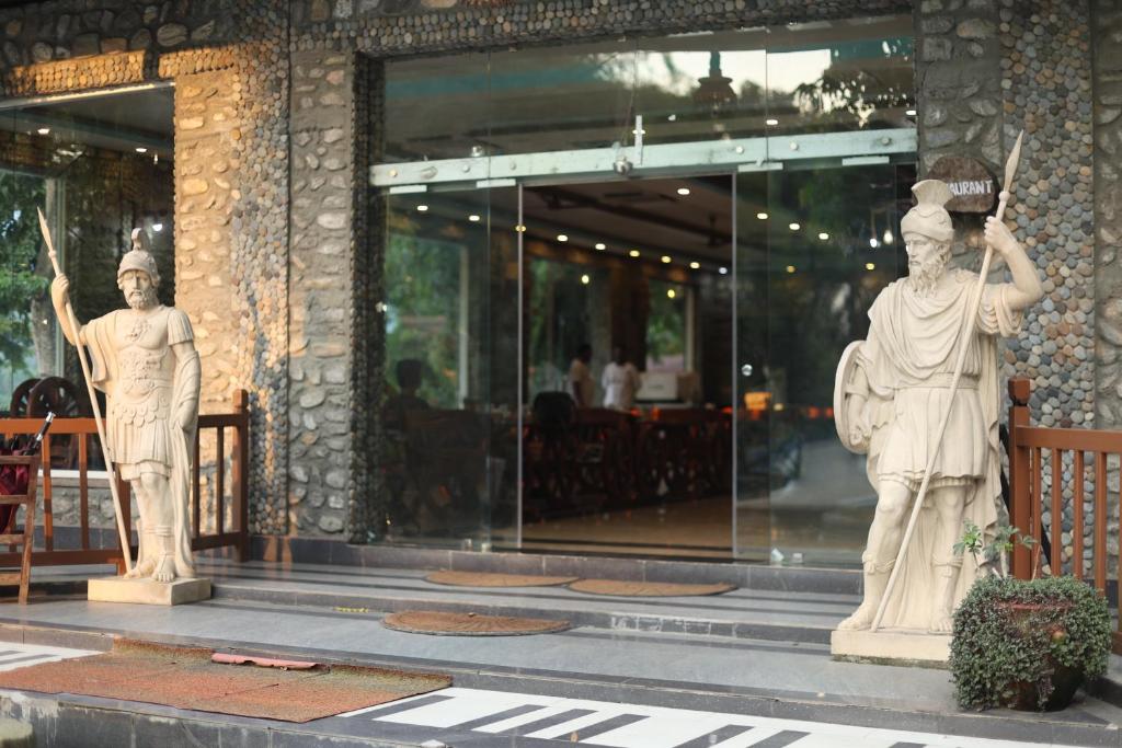 two statues of people standing outside of a building at Thimura Resort in Bharatpur