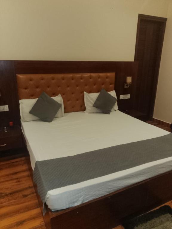 a bed with a wooden headboard and pillows on it at Hotel Harmony in Kharar
