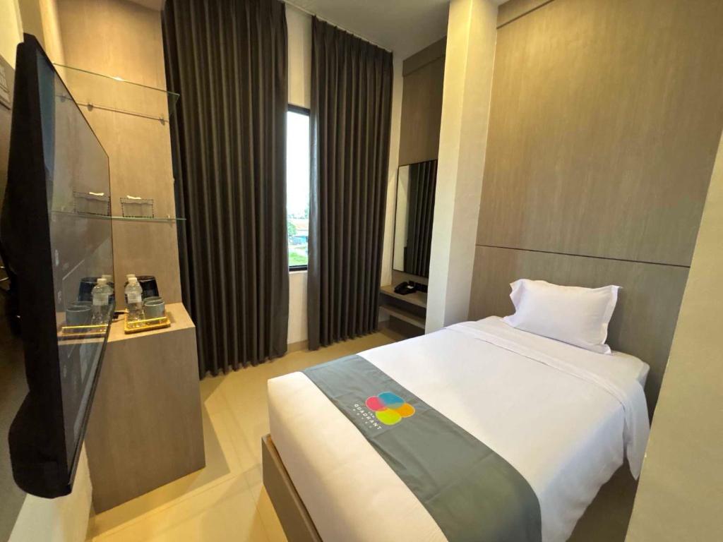 a hotel room with a bed and a television at The Quadrant Hotel Ocarina Batam in Batam Center