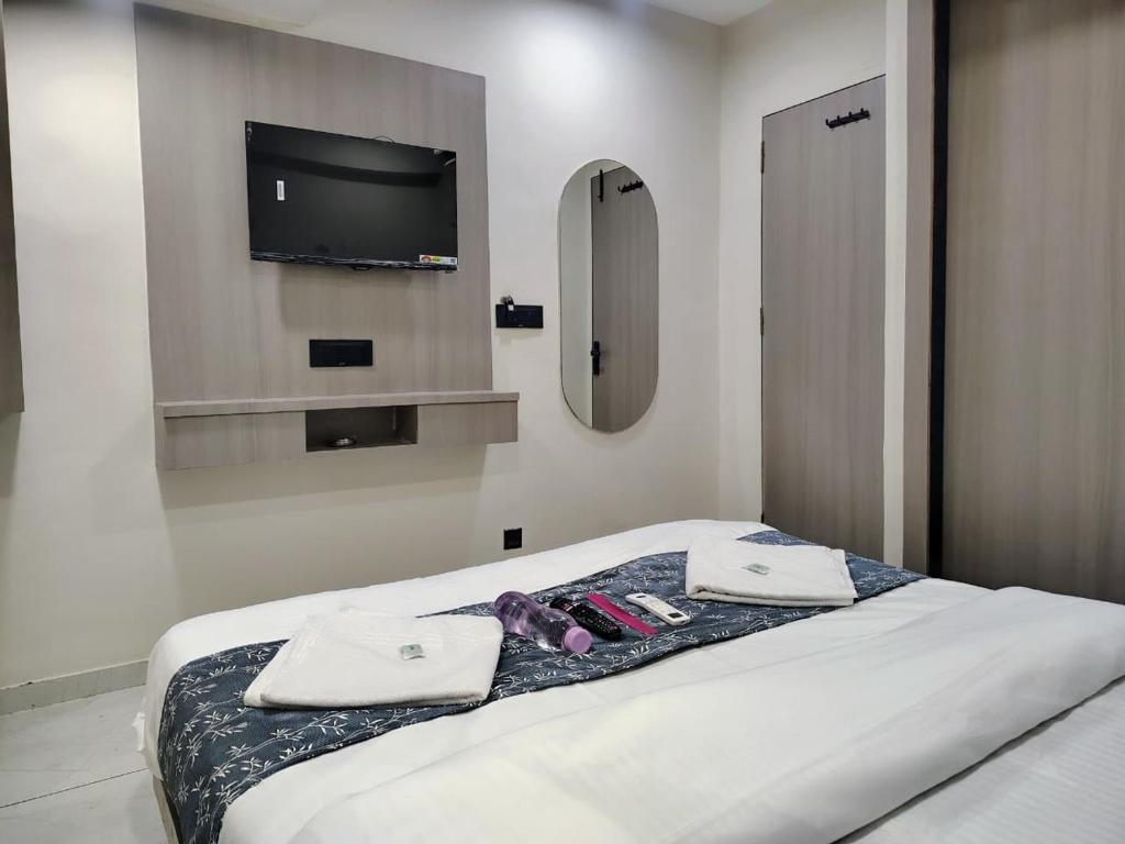 a bedroom with a bed with a tv on the wall at Hotel Sky Dream in Gandhinagar