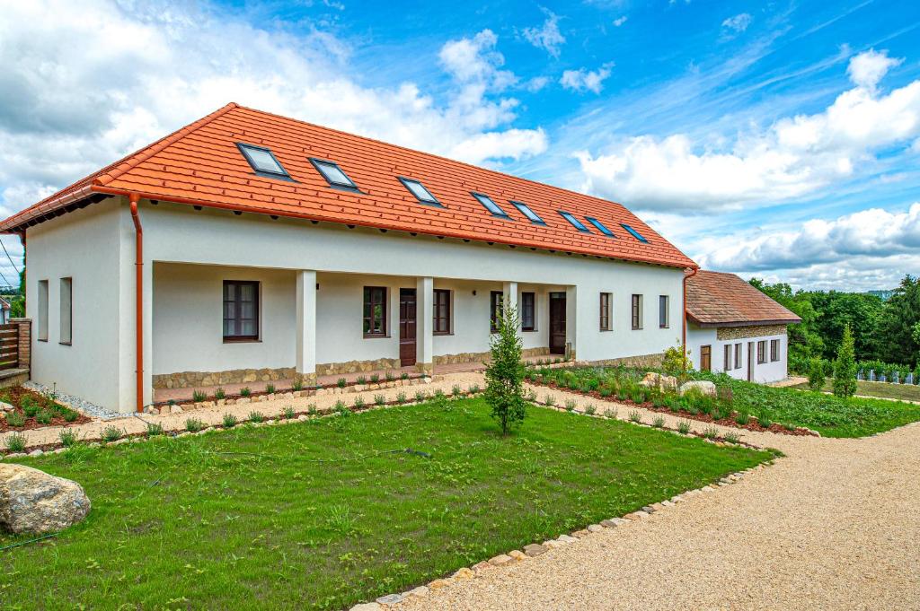 a house with an orange roof with a yard at Wathay Vendégház in Csesznek