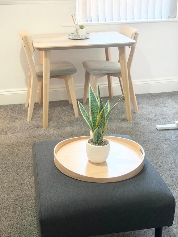 a table and chair with a potted plant on a ottoman at Relaxing Private Bedroom Stay in Hull