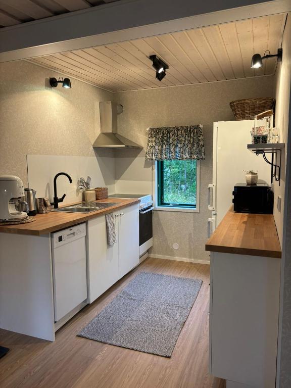 a kitchen with white cabinets and a counter top at En mysig liten Stuga nära naturen och havet in Västlax