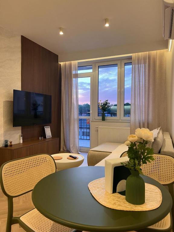a living room with a couch and a table with flowers on it at Kresowy View Apartment in Biłgoraj