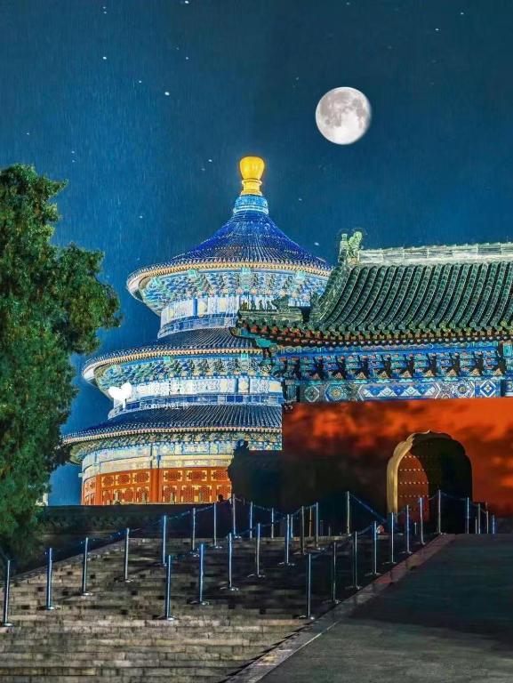 a large building at night with the moon in the sky at Happy Dragon Alley Hotel Beijing Tian An Men Forbidden City in Beijing