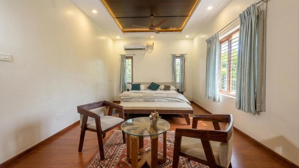 a living room with a bed and a table and chairs at The Grand Villa Kochi in Cochin