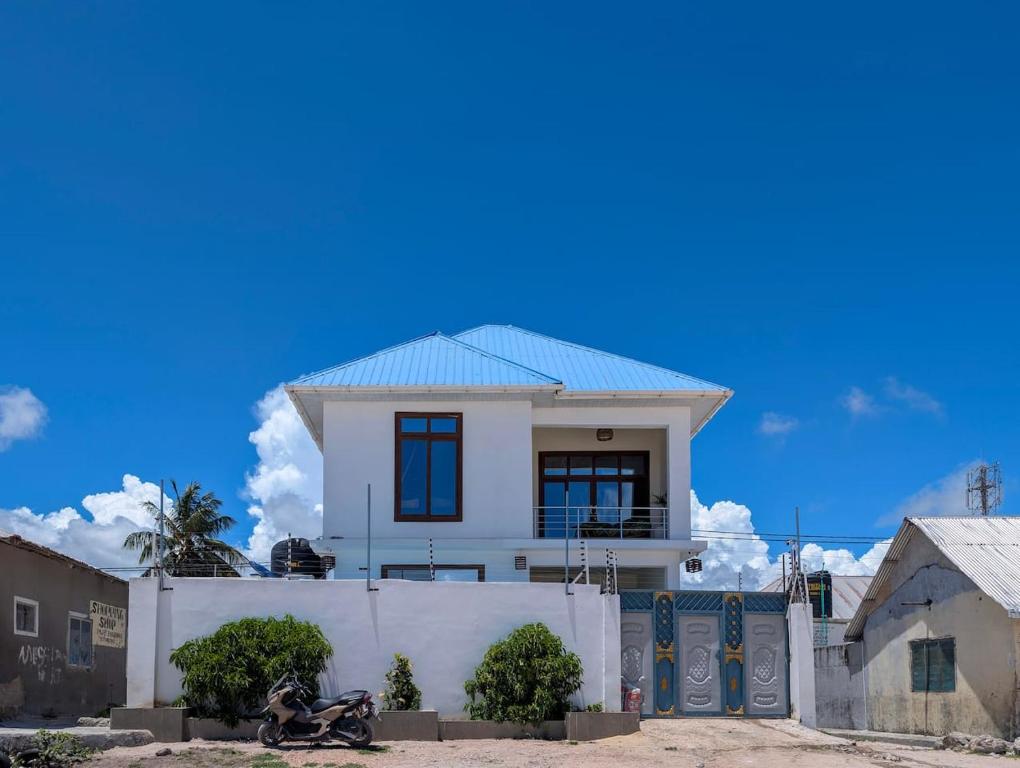 a white house with a blue roof behind a fence at Villa Goli 3BR Private Pool Villa, Paje in Zanzibar City