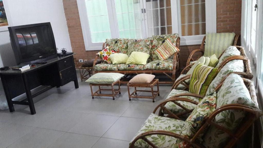 a living room with couches and a flat screen tv at Casa c/ churrasqueira próximo à praia em Ubatuba in Ubatuba