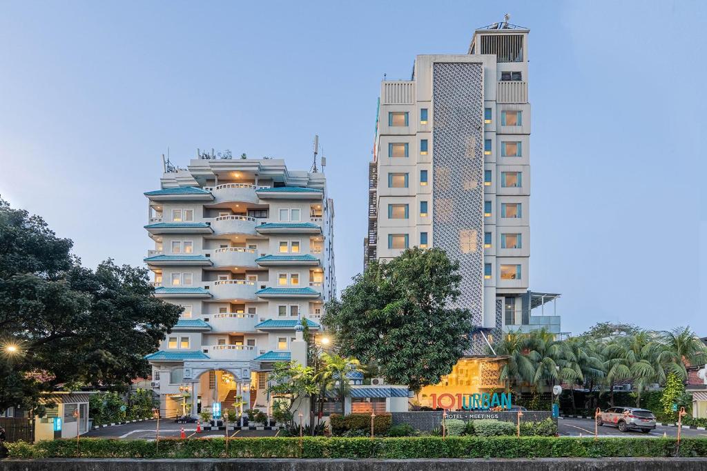 two tall buildings next to a street with trees at 1O1 URBAN Jakarta Thamrin in Jakarta
