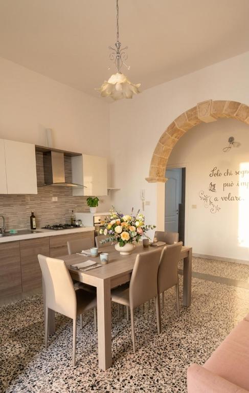 a dining room with a table and chairs and a kitchen at L'appartamento di Tricase in Tricase