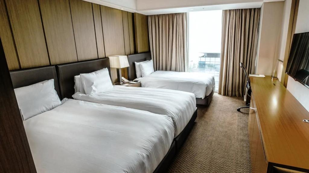 a hotel room with two beds and a television at LOTTE CITY HOTEL Daejeon in Daejeon