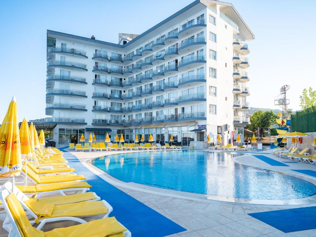 a hotel swimming pool with yellow lounge chairs and a hotel at Arora Hotel in Kuşadası