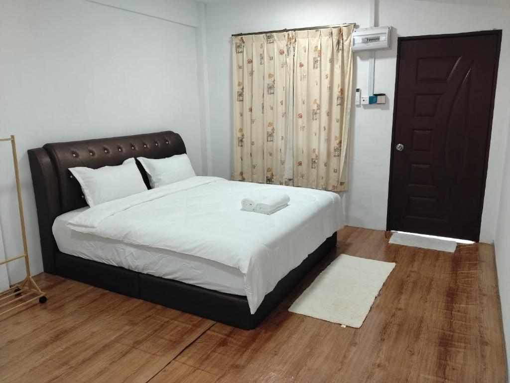 a bedroom with a bed with a black headboard and a door at HG Homestay in Kota Kinabalu
