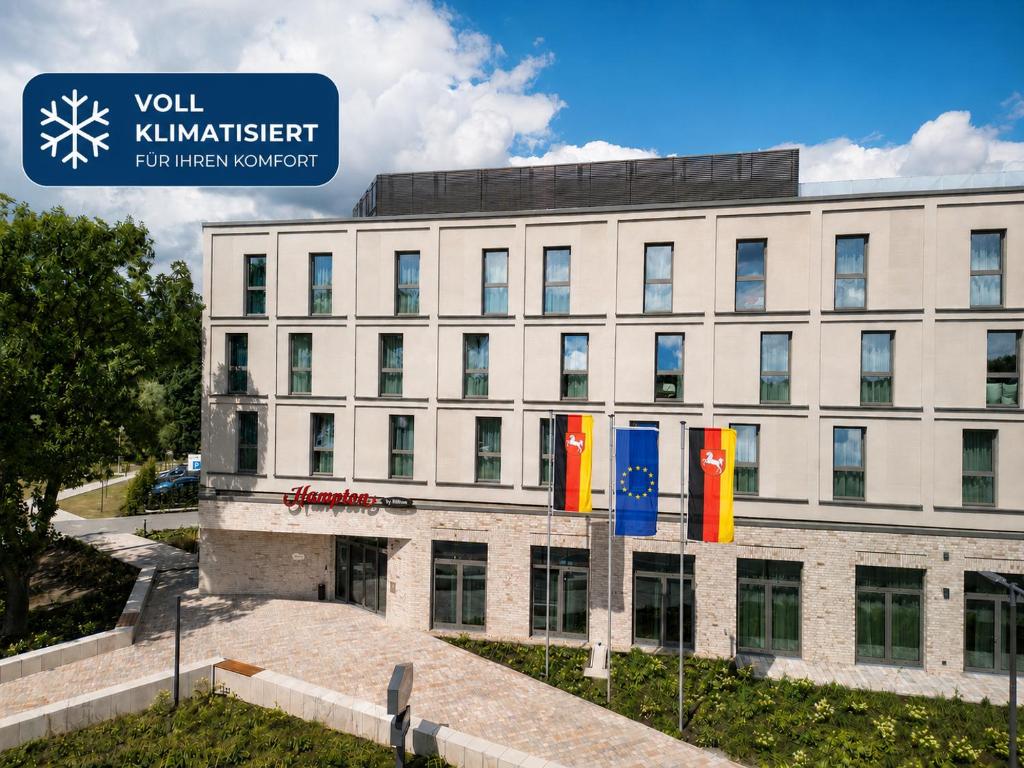 a building with colorful flags in front of it at Hampton By Hilton Celle in Celle