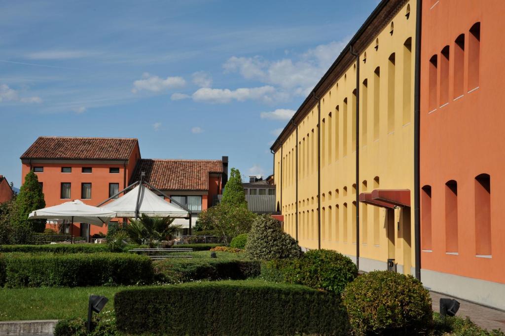 a building with bushes and trees next to a building at Hotel Filanda in Cittadella