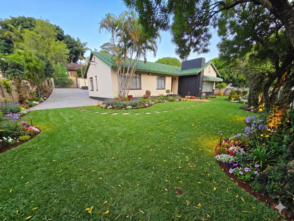 a house with a yard with green grass and flowers at Moxley Manor in Durban