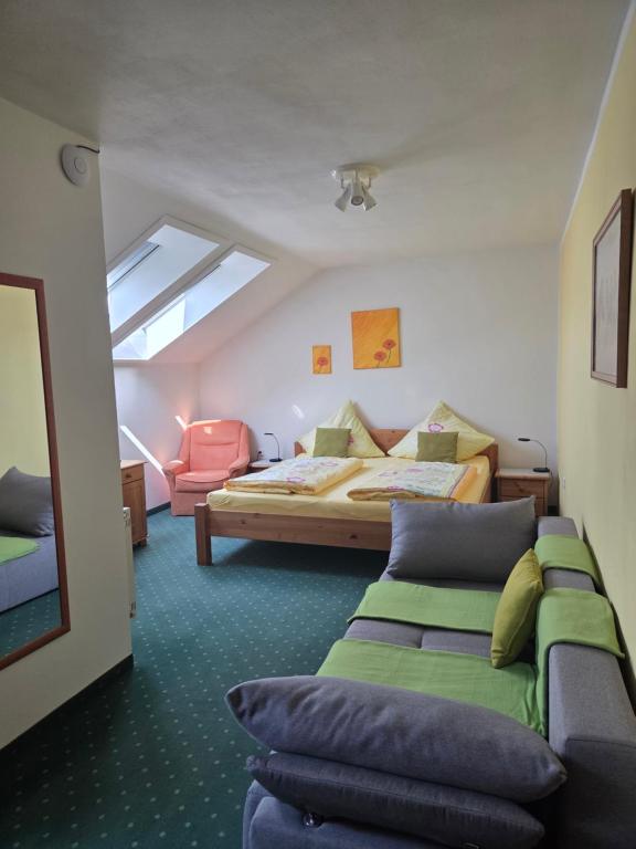 a bedroom with a bed and a couch and a window at Pension Eva in Domažlice