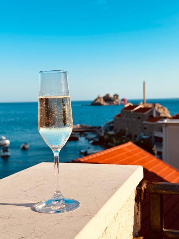 a glass of wine sitting on a ledge overlooking the ocean at Apartments MUN Petrovac in Petrovac na Moru