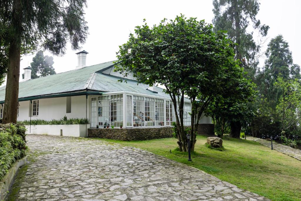 a white house with a tree in front of it at Singell Tea Estate - A CGH Earth Experience in Darjeeling