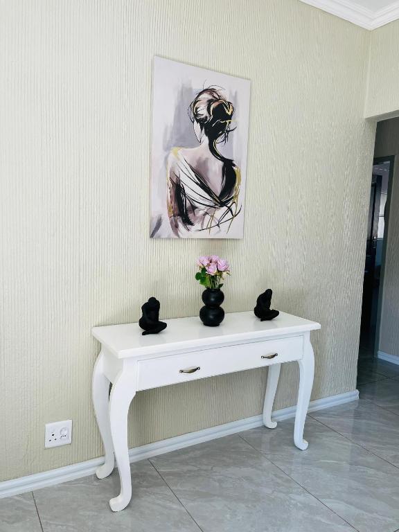 a white table with a vase of flowers on it at No 80 At Erasmus in Polokwane