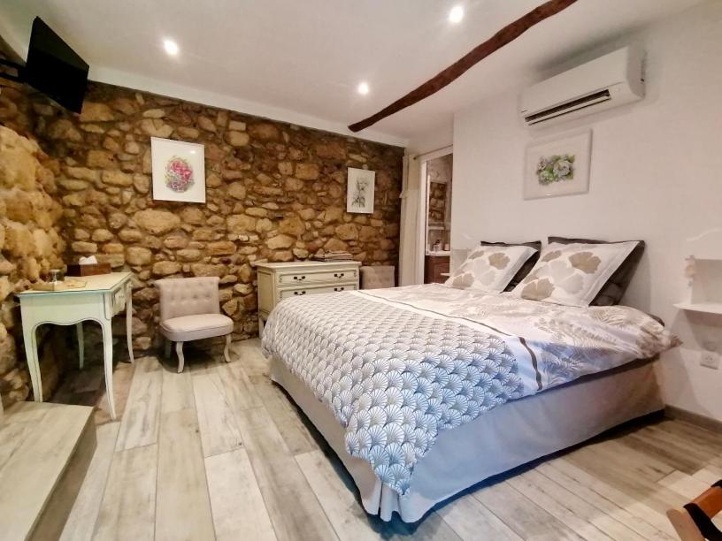 a bedroom with a bed and a stone wall at Mas de lasquiers in Saint-Paul-le-Jeune