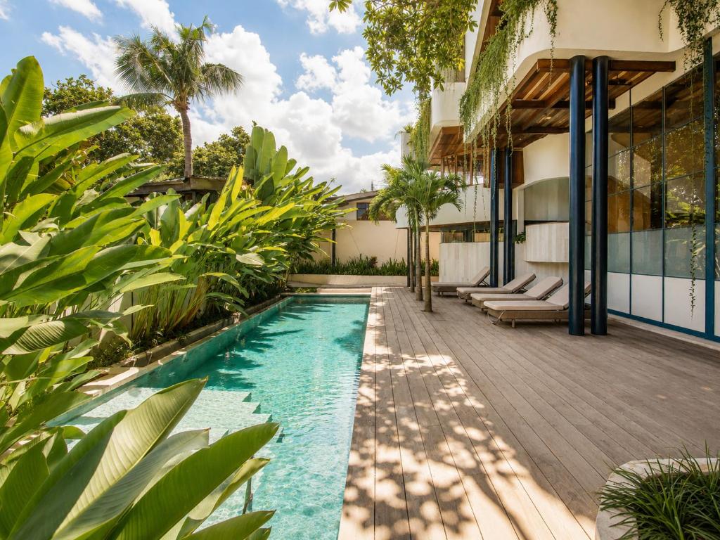 a pool in the backyard of a house with plants at Modern 1-BR Loft with Art Deco Style Shared Pool in Canggu