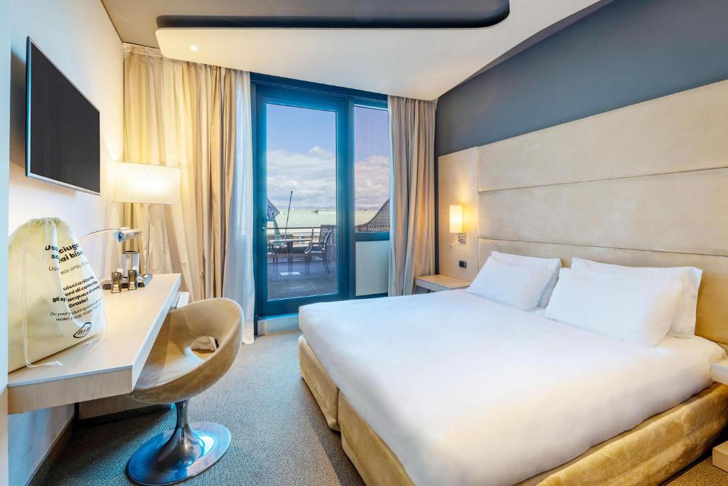 a hotel room with a bed and a desk and a window at B&B HOTEL Expo Verona Villafranca in Villafranca di Verona