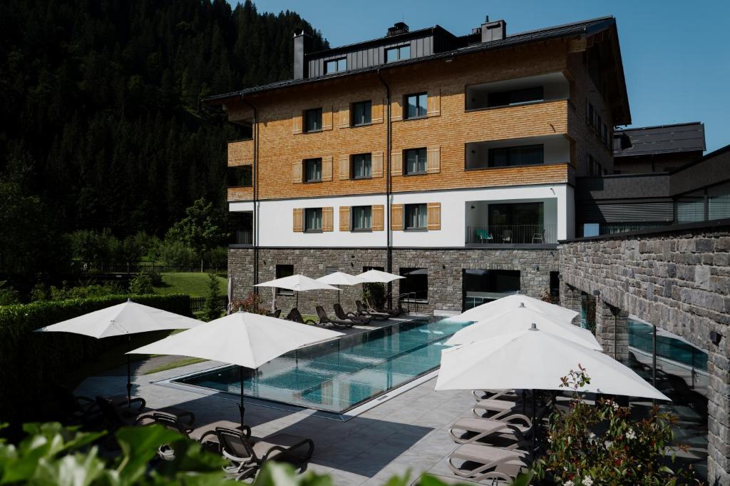 a hotel with a swimming pool and umbrellas at ArlbergResort Klösterle in Klösterle