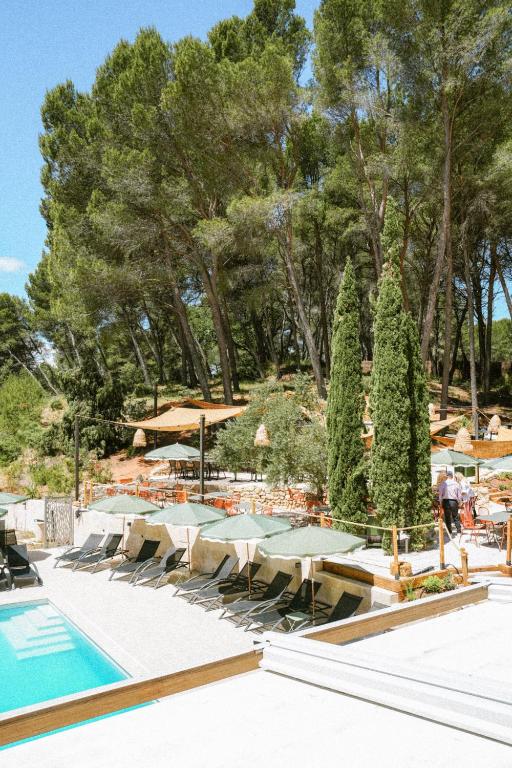 a swimming pool with tables and chairs and trees at Domaine de l'Oustalia in Aix-en-Provence