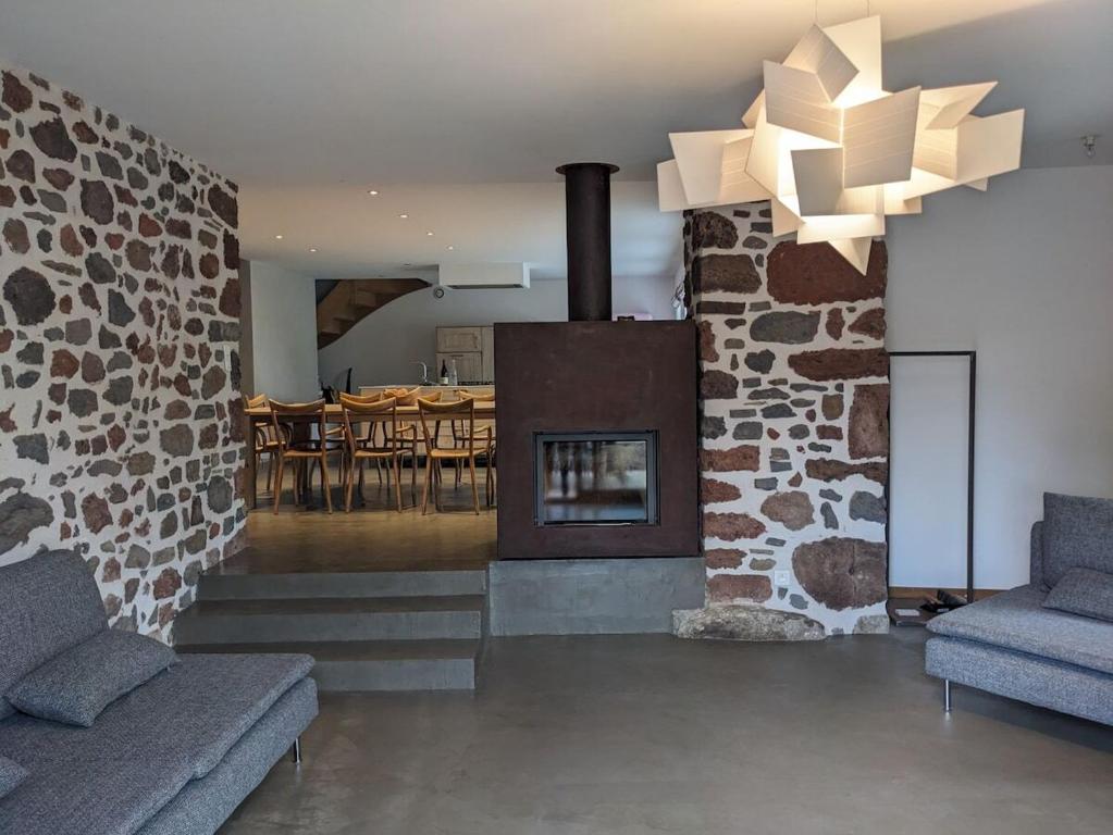 a living room with a stone fireplace and a dining room at Maison de vacances tout Confort au Calme avec Jardin clos in Saint-Just-près-Brioude
