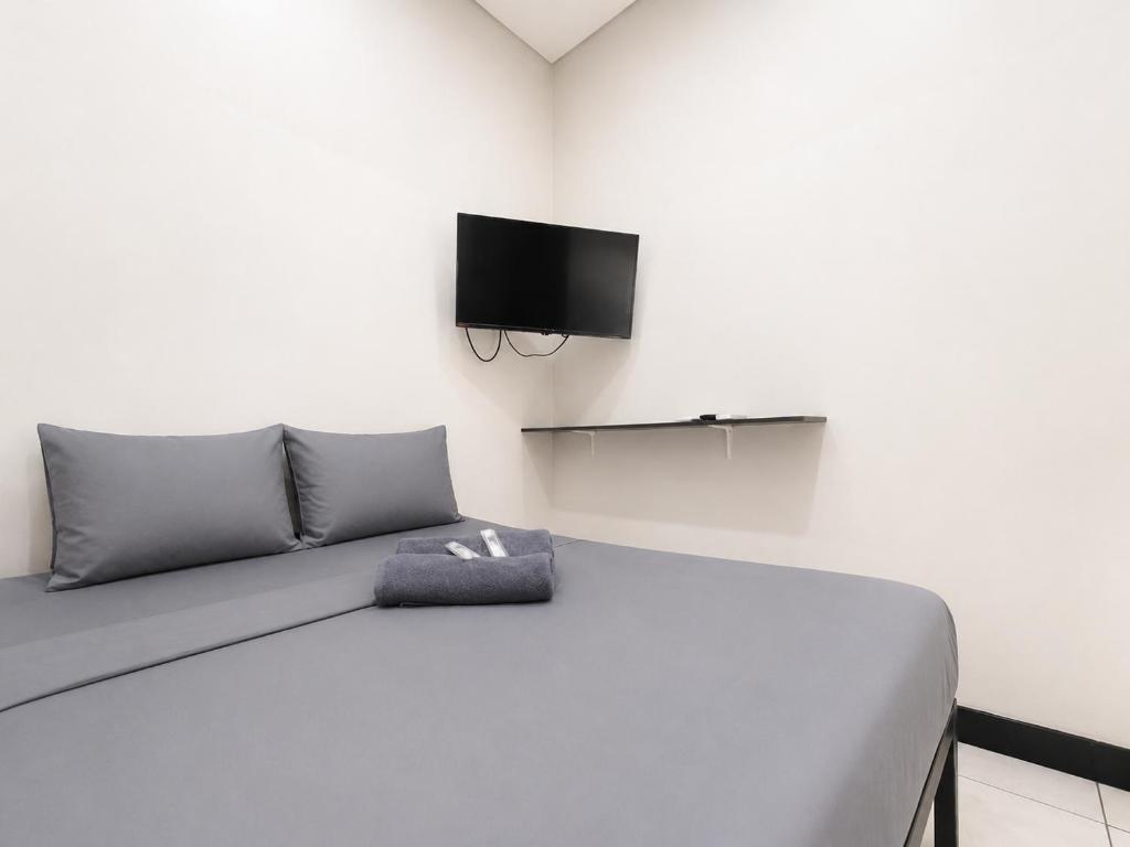 a bedroom with a bed with a tv on the wall at NamRoom at Kalimalang in Cibening
