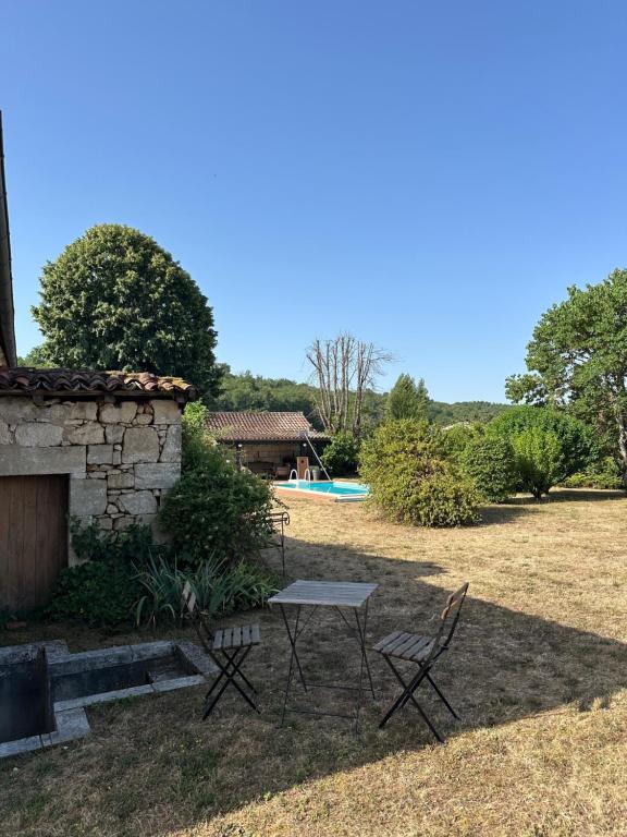 a table and chairs in a yard with a pool at Chambre d'hôtes bed and breakfast in La Chapelle-Faucher