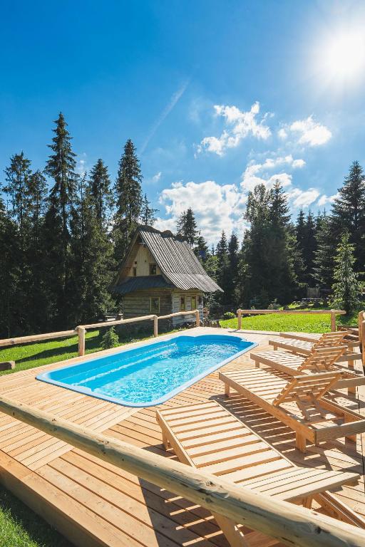 a swimming pool with a wooden deck and a house at Zagroda Krowiarki Chochołów in Chochołów