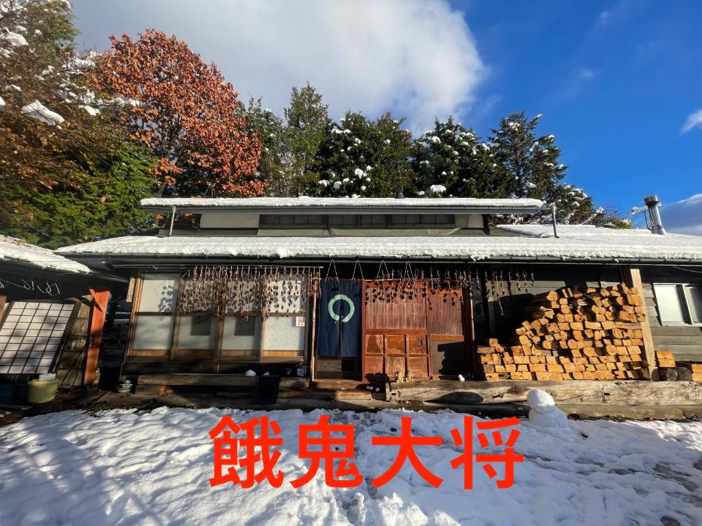 a house with a sign in the snow at 一棟貸しの宿 餓鬼大将と別館トキワ荘 in Omachi