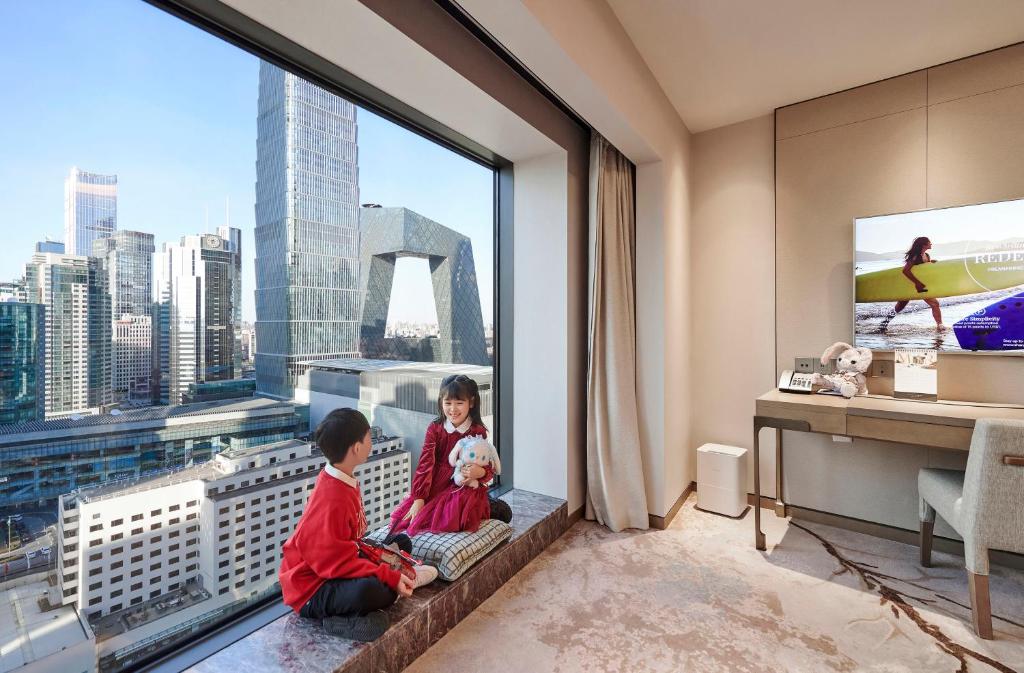 two children sitting in a room with a large window at China World Hotel, Beijing, A Shangri-La Hotel in Beijing