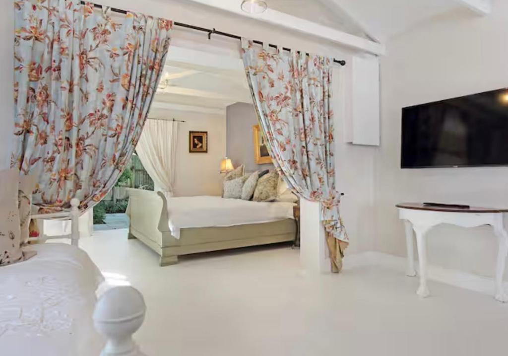 a living room with a bed and a tv at Constantia French Cottage in Sweet Valley