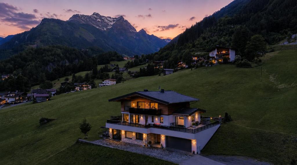 a house on a hill with mountains in the background at Appartment Sonnenwiese in Finkenberg