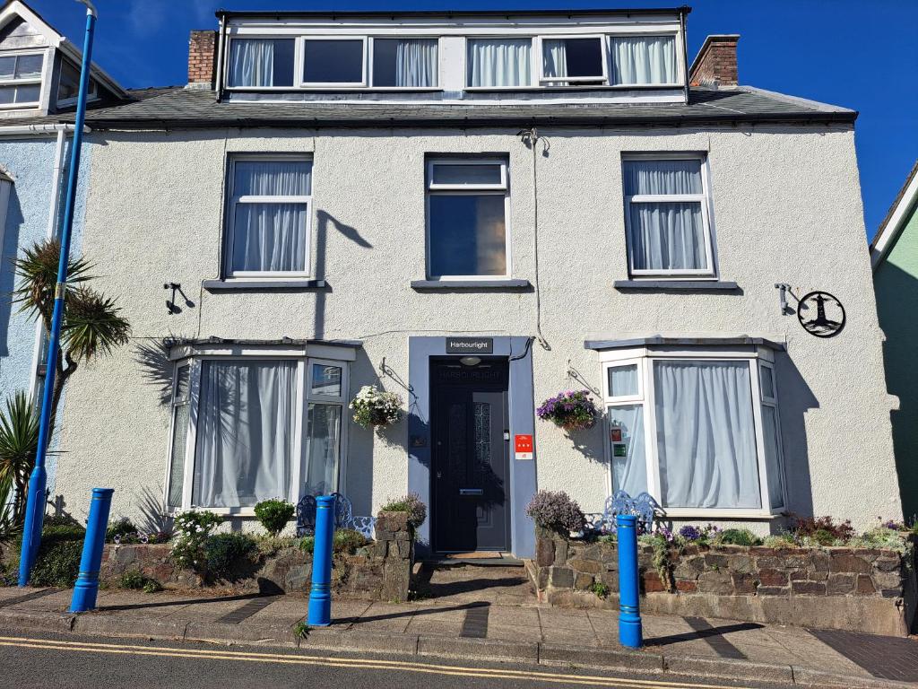a white house with a blue door on a street at Harbourlight Guesthouse in Saundersfoot