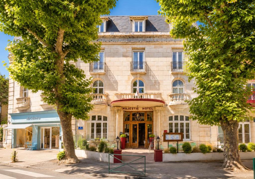 a large stone building with trees in front of it at LOGIS Hotel Majestic Chatelaillon Plage - La Rochelle in Châtelaillon-Plage