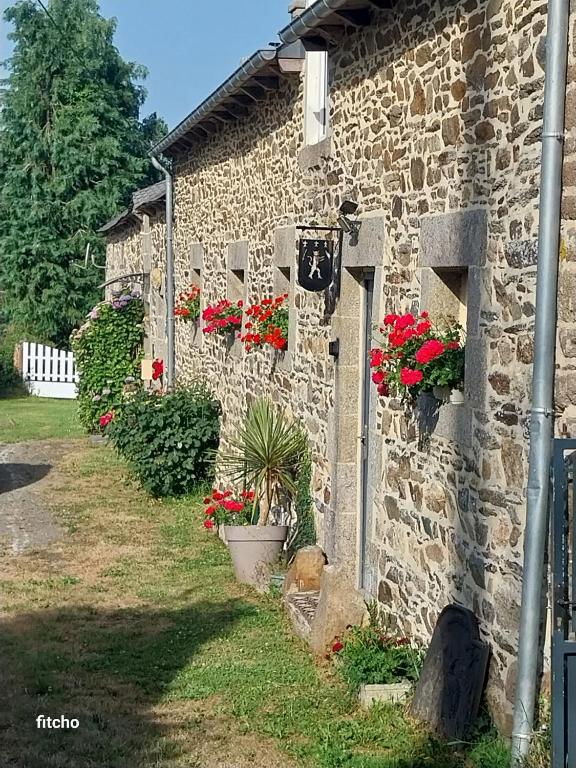 a stone building with flowers on the side of it at L'abreuvoir du Leffo in Allineuc