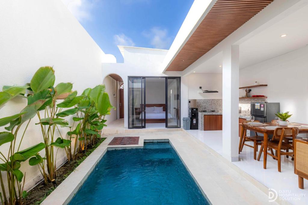 a swimming pool in a villa with a dining room and kitchen at Villa didi By sedana cottage in Pererenan