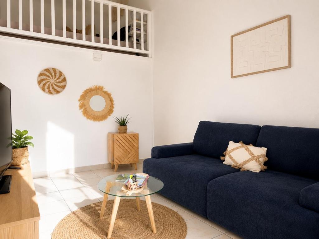 a living room with a blue couch and a glass table at Azuri Lodge Piscine Privée Marina Golf in Saint-François