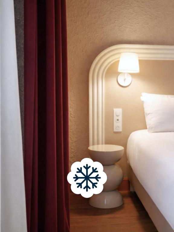 a hotel room with a bed and a snowflake on a lamp at Résidence les Dômes par Vy Resort Thermal & Spa in Vichy