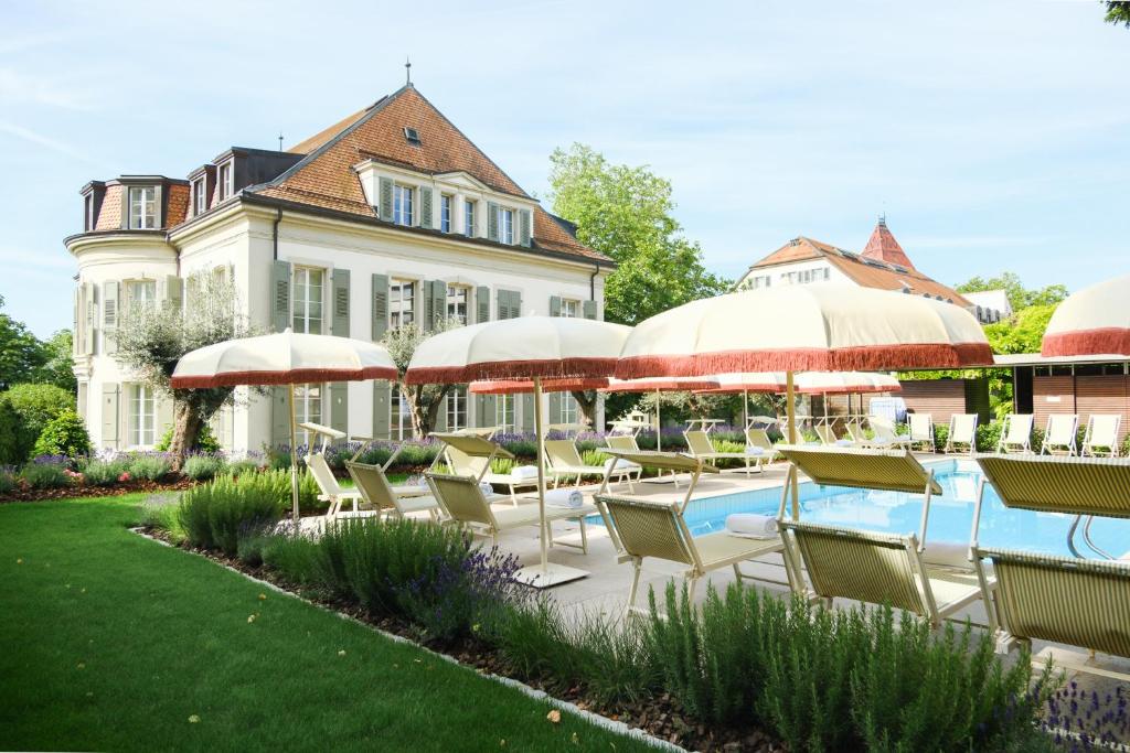 a pool with chairs and umbrellas in front of a building at Hotel Angleterre in Lausanne