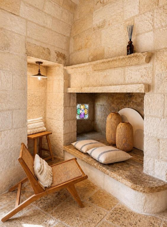 a living room with a stone fireplace with a bench at Pètra Boutique Home by Symphonya Luxury Holiday Rentals in Scorrano