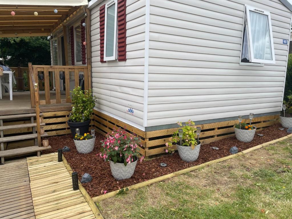 a porch with three potted plants on the side of a house at L'échapée verte in Litteau