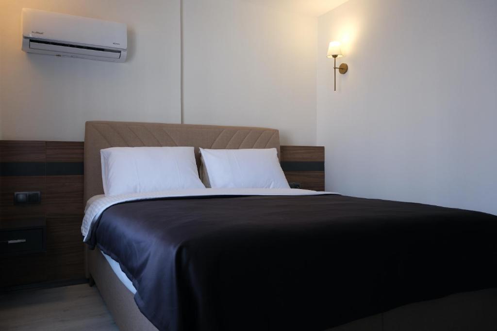 a bed with a black blanket and white pillows at Üstün Hotel Alsancak in İzmir