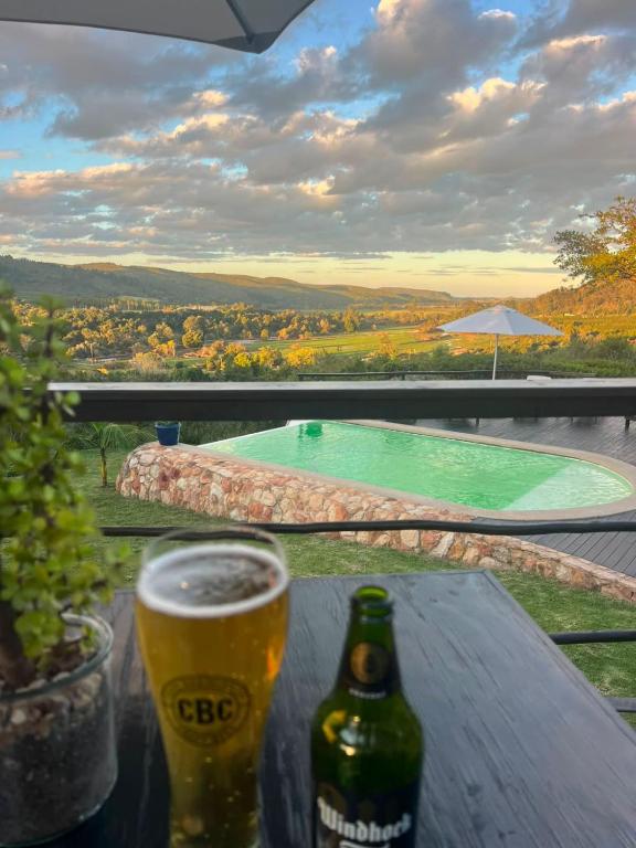 a glass of beer sitting on a table next to a pool at Howberry Hills in Plettenberg Bay