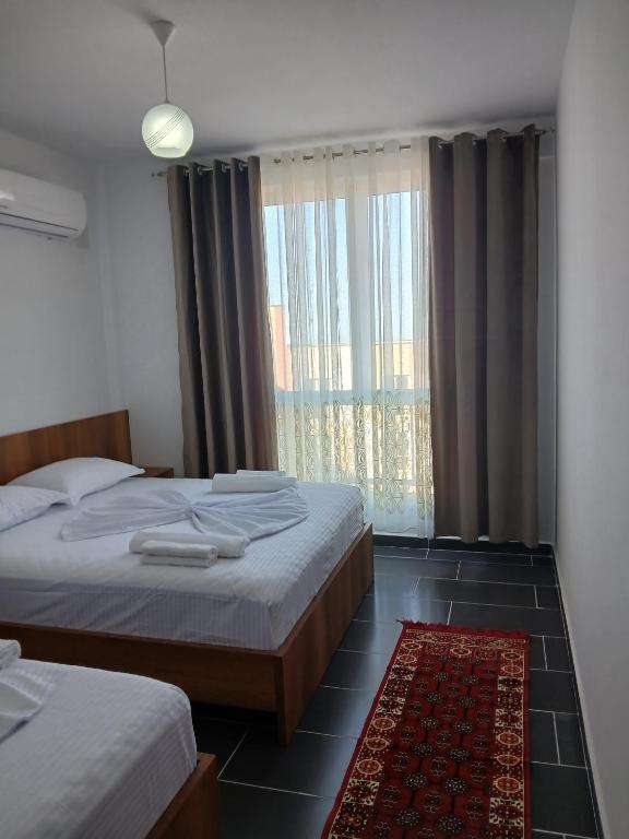a bedroom with two beds and a large window at Enes apartament in Krujë