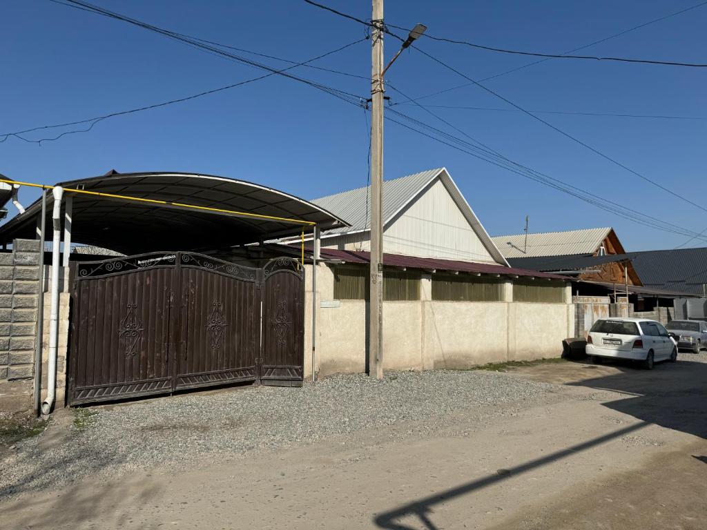 a house with a gate and a car parked in a driveway at Дом in Bishkek